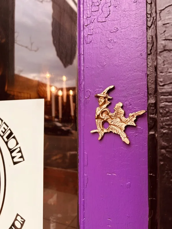 The purple doorway of As Above So Below with a golden witch ornament